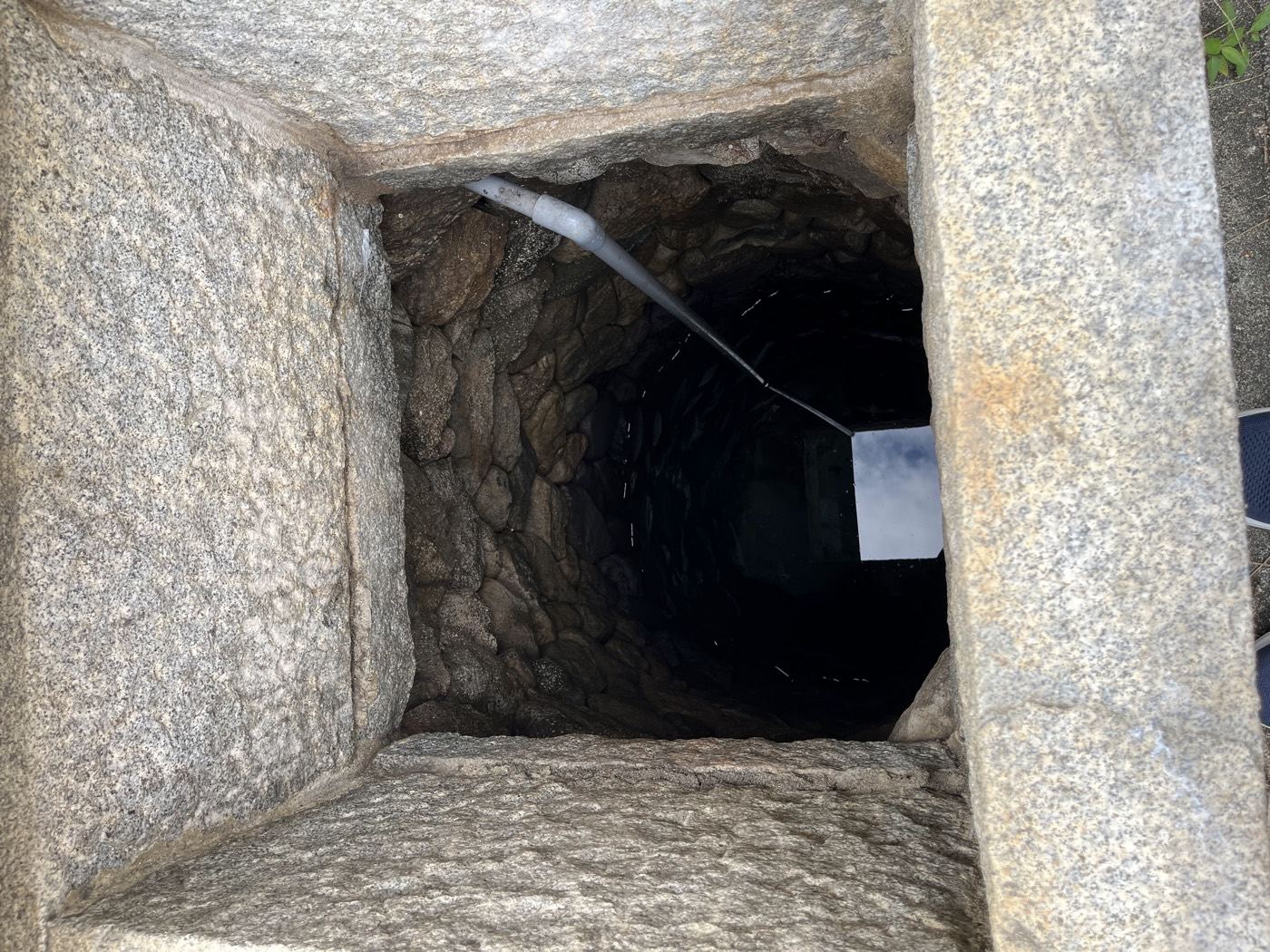 伊賀・阿保の家の敷地に残る井戸。石を積んだ内壁の底に、いまも水がたまっている。